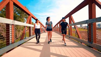 Three people are walking on a bridge.